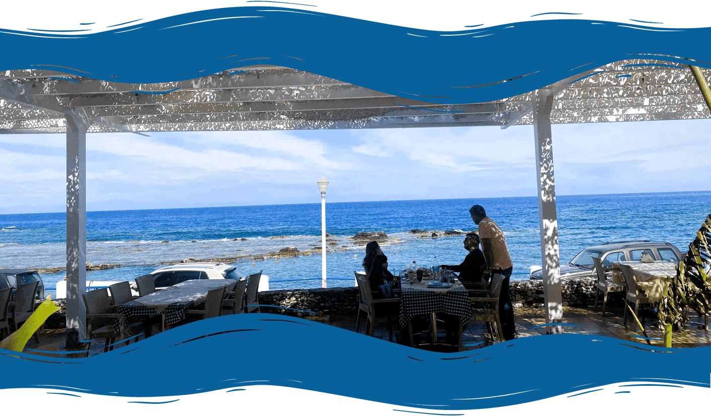 Family and friends at Psarolimano eating and chatting together fresh fish by the sea.