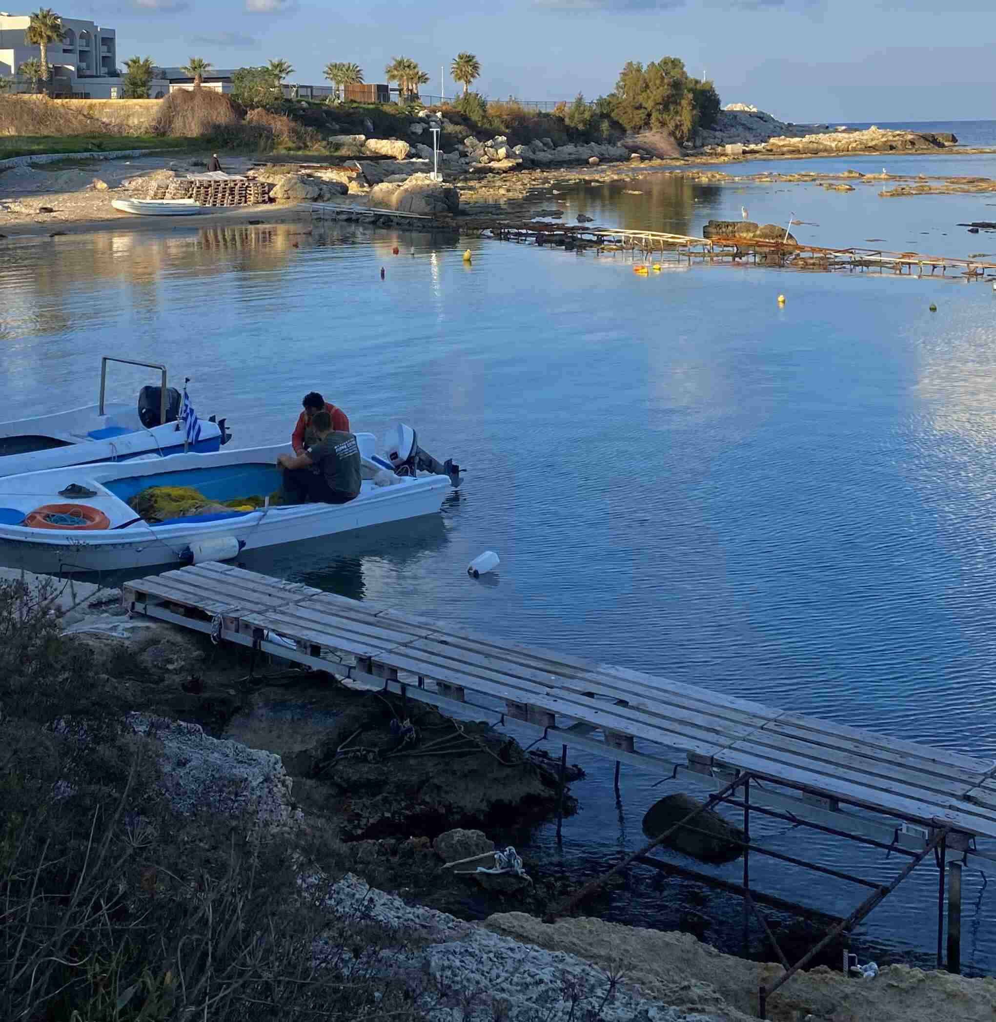 Two people on the boat infront of psarolimano delivering fresh fishes to the restaurant.